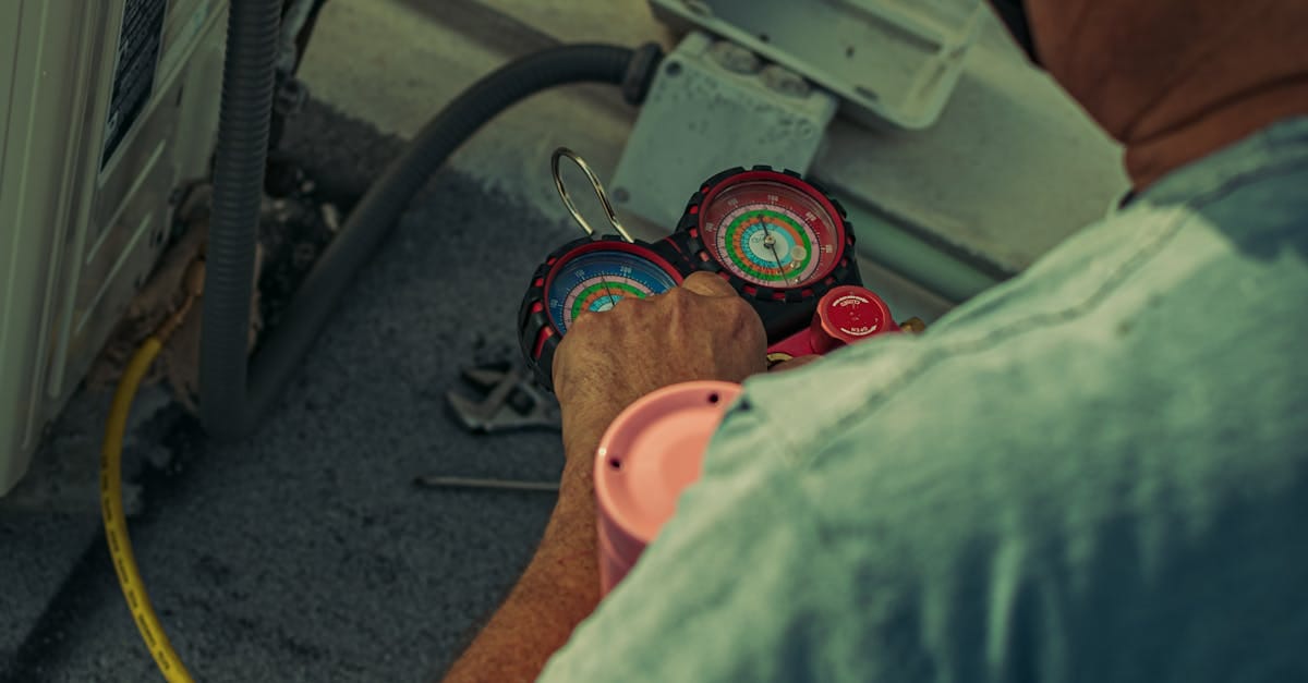 Professional technician repairing an outdoor air conditioning unit with gauges and tools.
